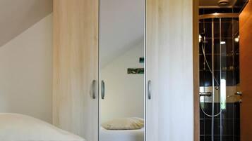 A bedroom with a bed, a wardrobe, and a shower area.