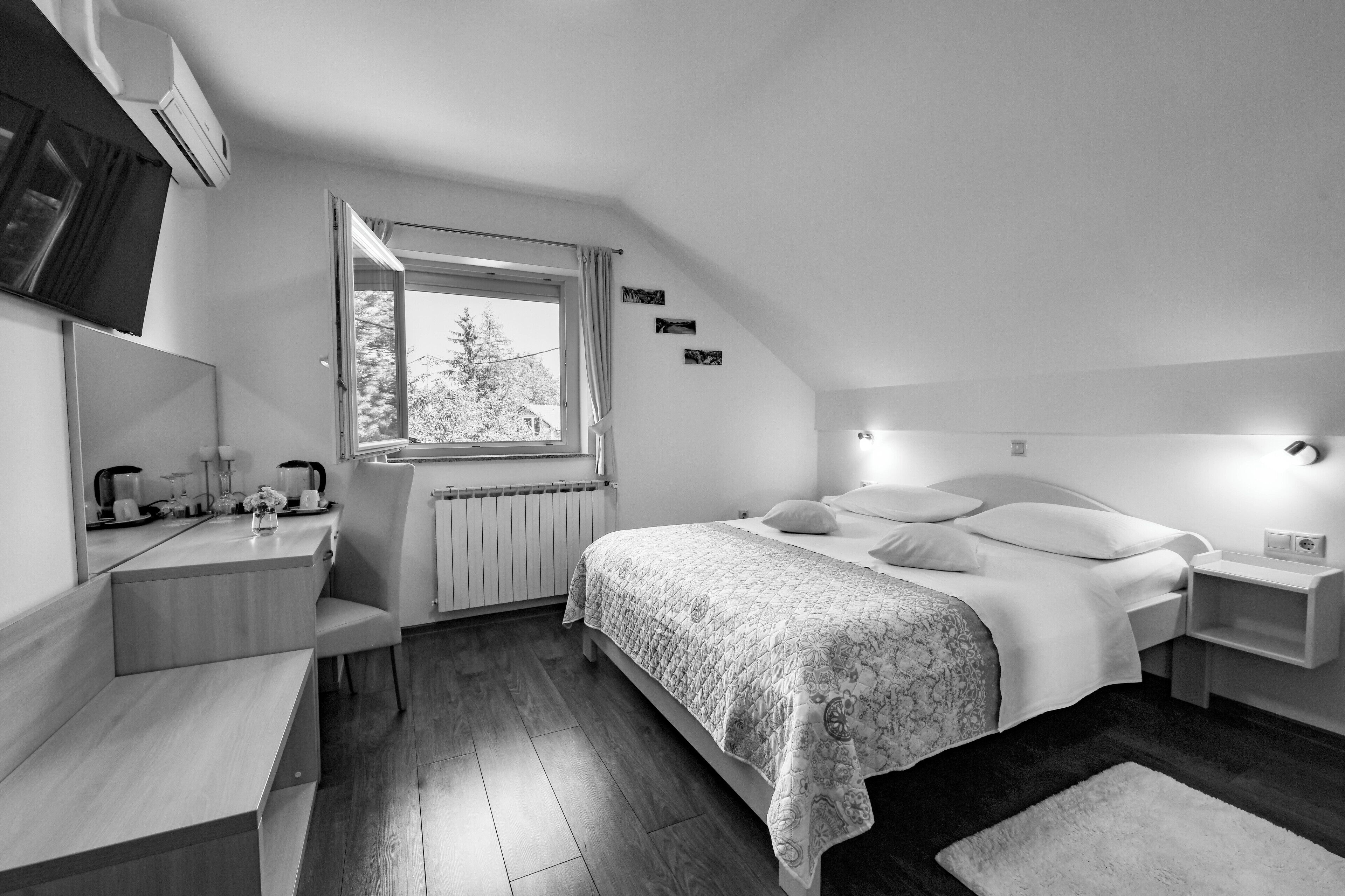 A modern bedroom with a bed, bedside tables, a desk, and a window.