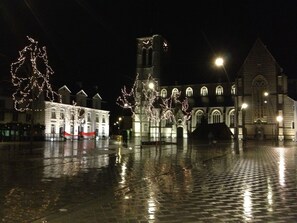 A historic square with a church, a bell tower, and illuminated trees.