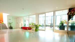 A spacious, modern interior with a red sofa, potted plants, and a staircase. - Corbie Geel (Geel)