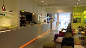 A modern restaurant with a long counter, multiple seating areas, and a bright interior. - Corbie Geel (Geel)