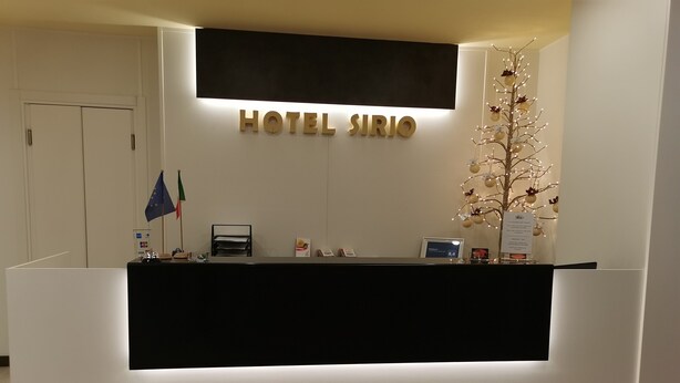 Una mesa de recepción de hotel con un letrero que dice "HOTEL SIRIO".