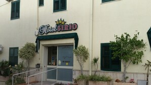Un edificio con un letrero que dice 'Hotel Sirio' y una escalera que lleva a la entrada.