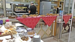 Mostrador de panadería con diversos productos horneados y una máquina de café.