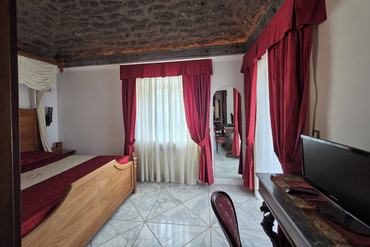 A bedroom with a bed, a TV, a desk, and a chair.