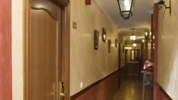 Un pasillo de hotel con puertas de madera, paredes color beige y una lámpara.