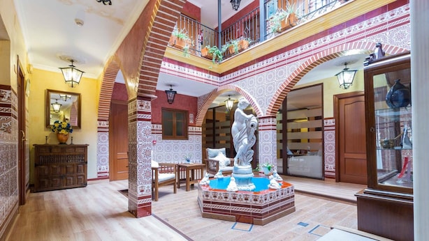 A spacious atrium with a central fountain, ornate tiled walls, and a high ceiling. - Hotel Esmeralda (Osuna)