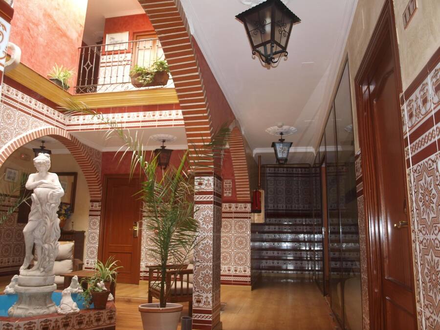 Un vestíbulo amplio con una escalera, una estatua y plantas en macetas.