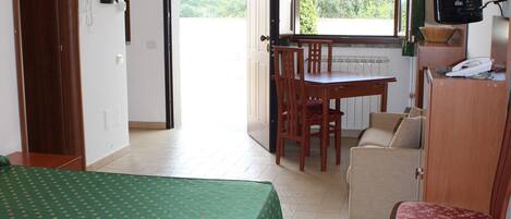 A room with a bed, a dining table, a sofa, and a television.