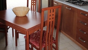 Una cocina con armarios de madera, una estufa a gas, un fregadero y una mesa de comedor con sillas.