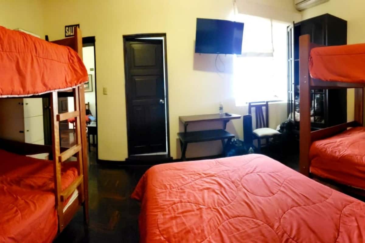 Ein Schlafsaalzimmer mit Etagenbetten, einem Schreibtisch, einem Stuhl und einem Fernseher.