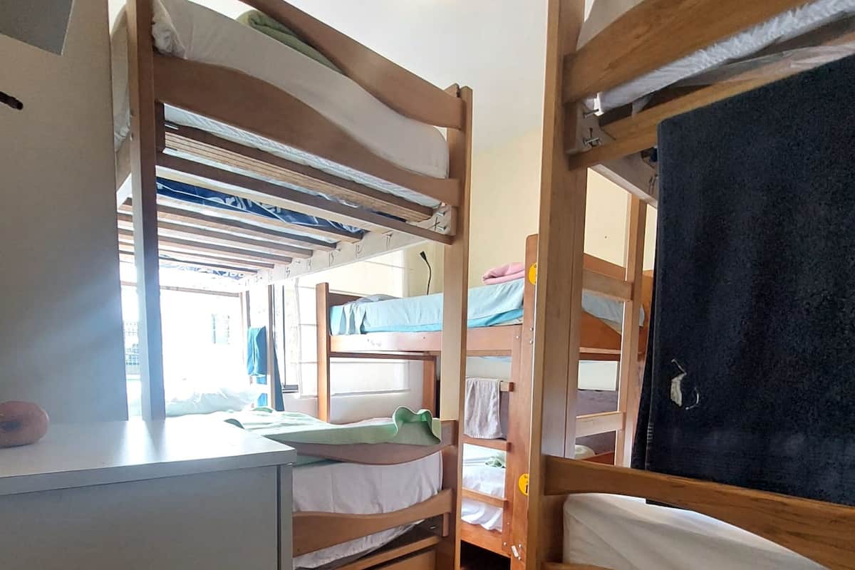 Ein Schlafsaalzimmer mit Etagenbetten, einem Schreibtisch und einem Fenster.