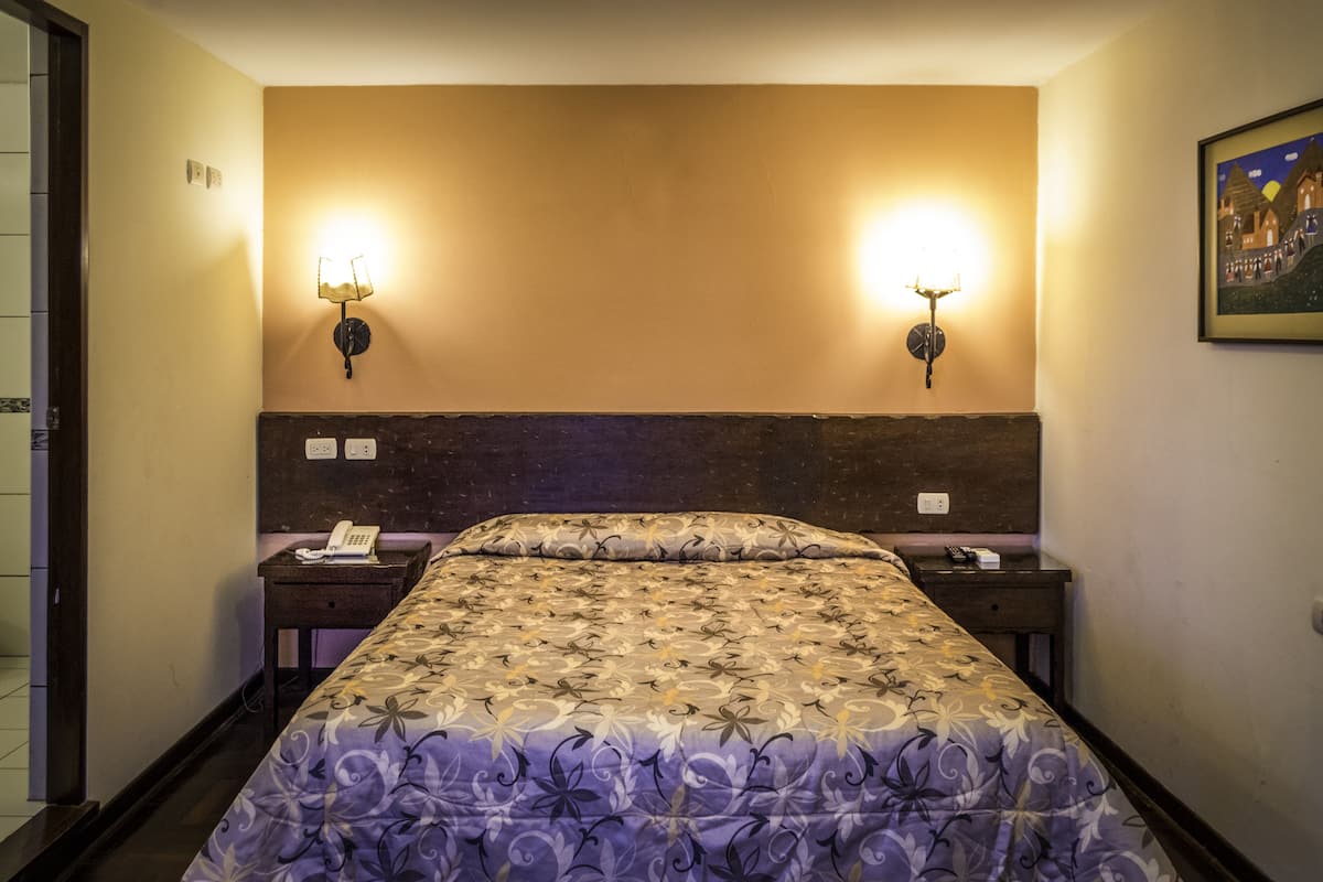 Ein Hotelzimmer mit einem großen Bett, zwei Nachttischen und Wandlampen.