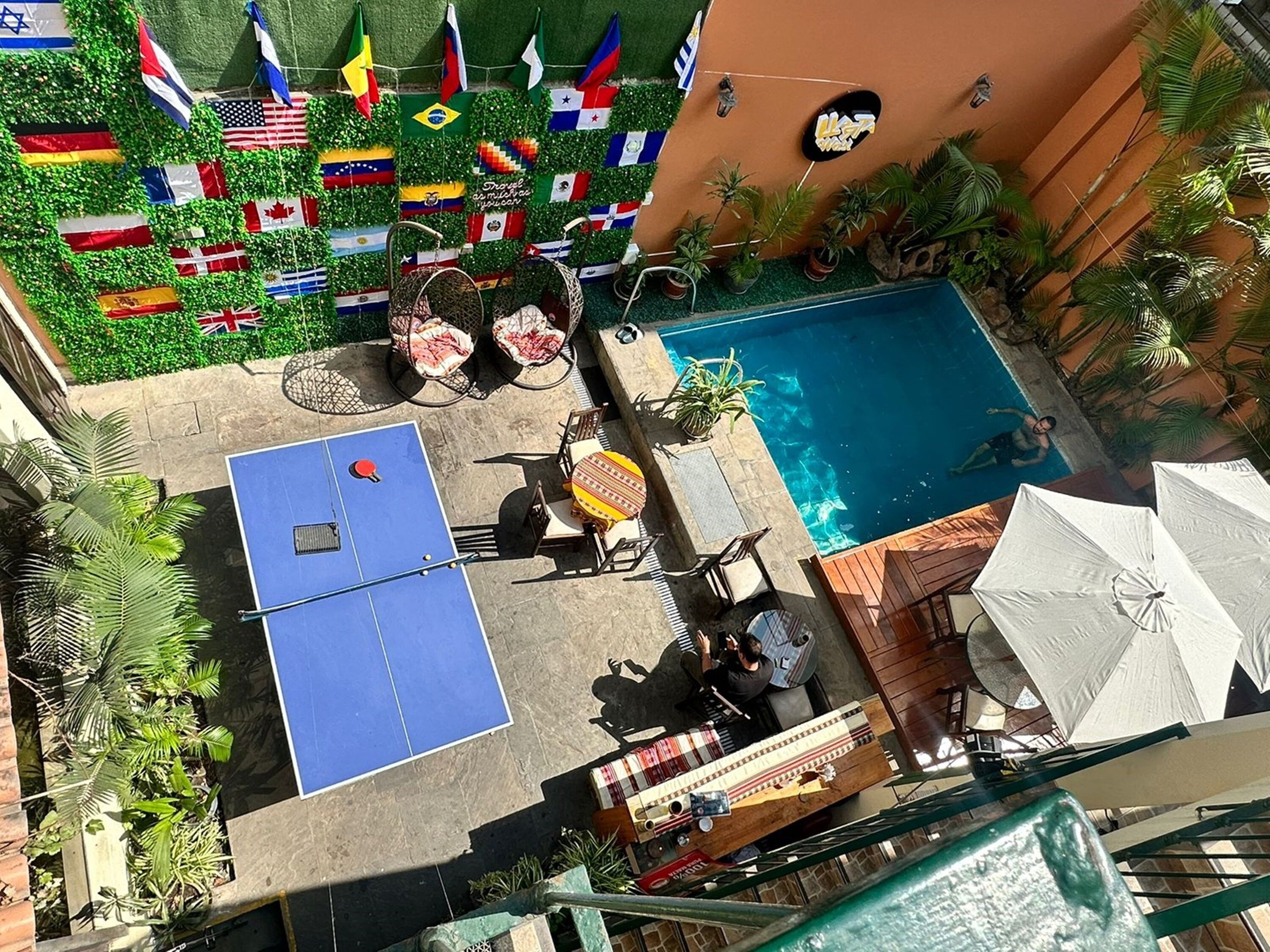 A rooftop pool area with multiple flags, a ping pong table, and outdoor seating.