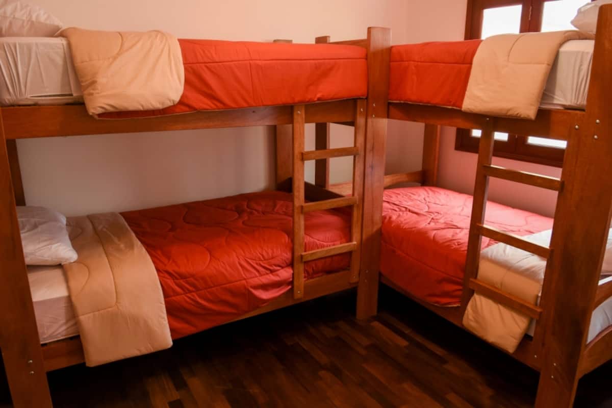 Ein Schlafzimmer mit Etagenbetten, Holzrahmen und roter Bettwäsche.
