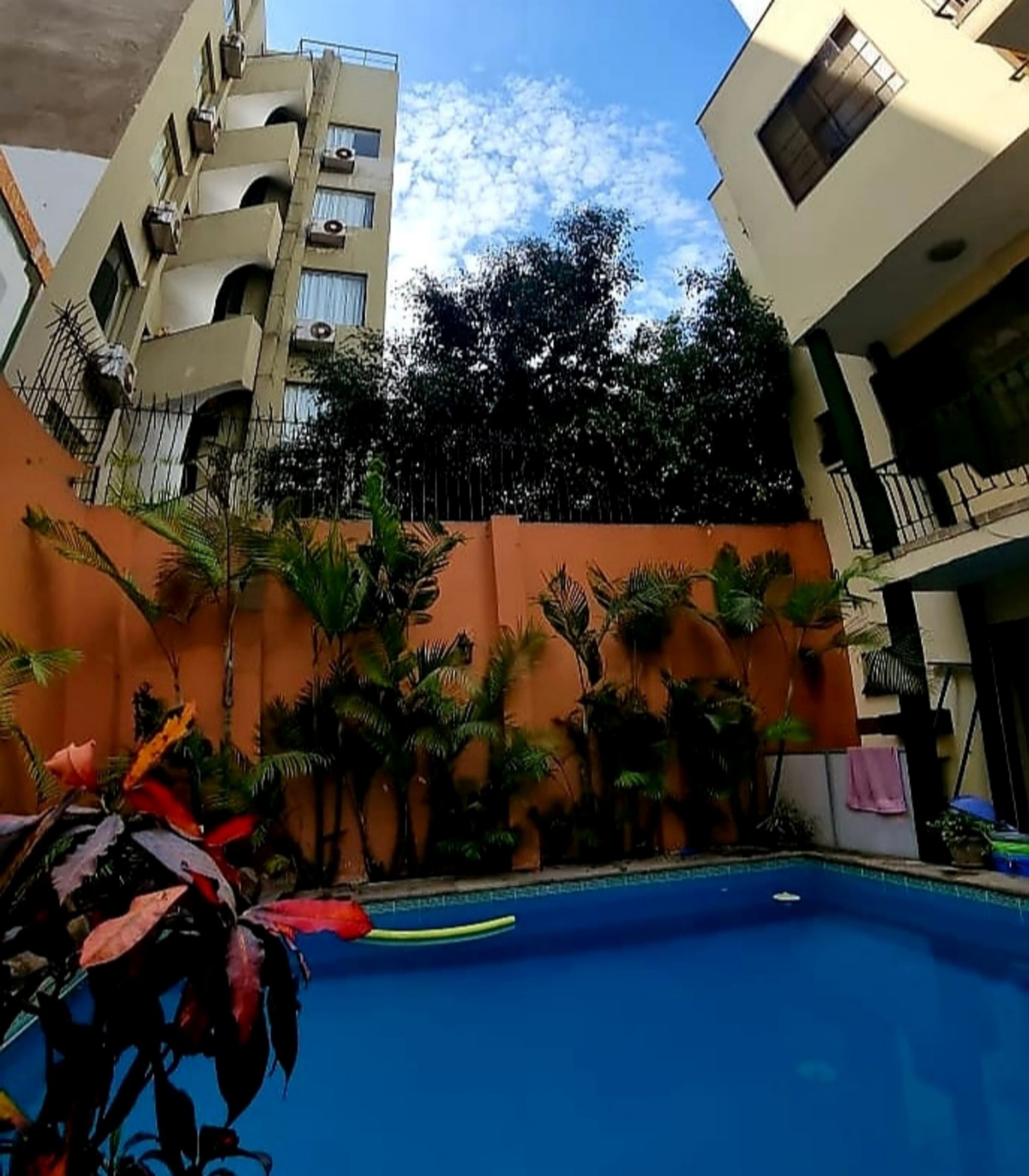 A swimming pool surrounded by palm trees and a building with balconies.
