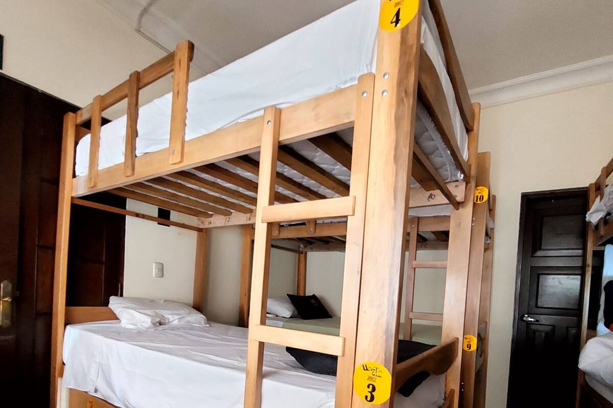 Ein Stockbett mit Holtzargen und weißer Bettwäsche. Die Bettpfosten sind mit Nummern versehen.