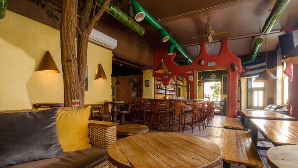 L’intérieur de ce restaurant est chaleureux, avec des tables en bois, un coin bar et un espace détente comprenant un canapé et des coussins.