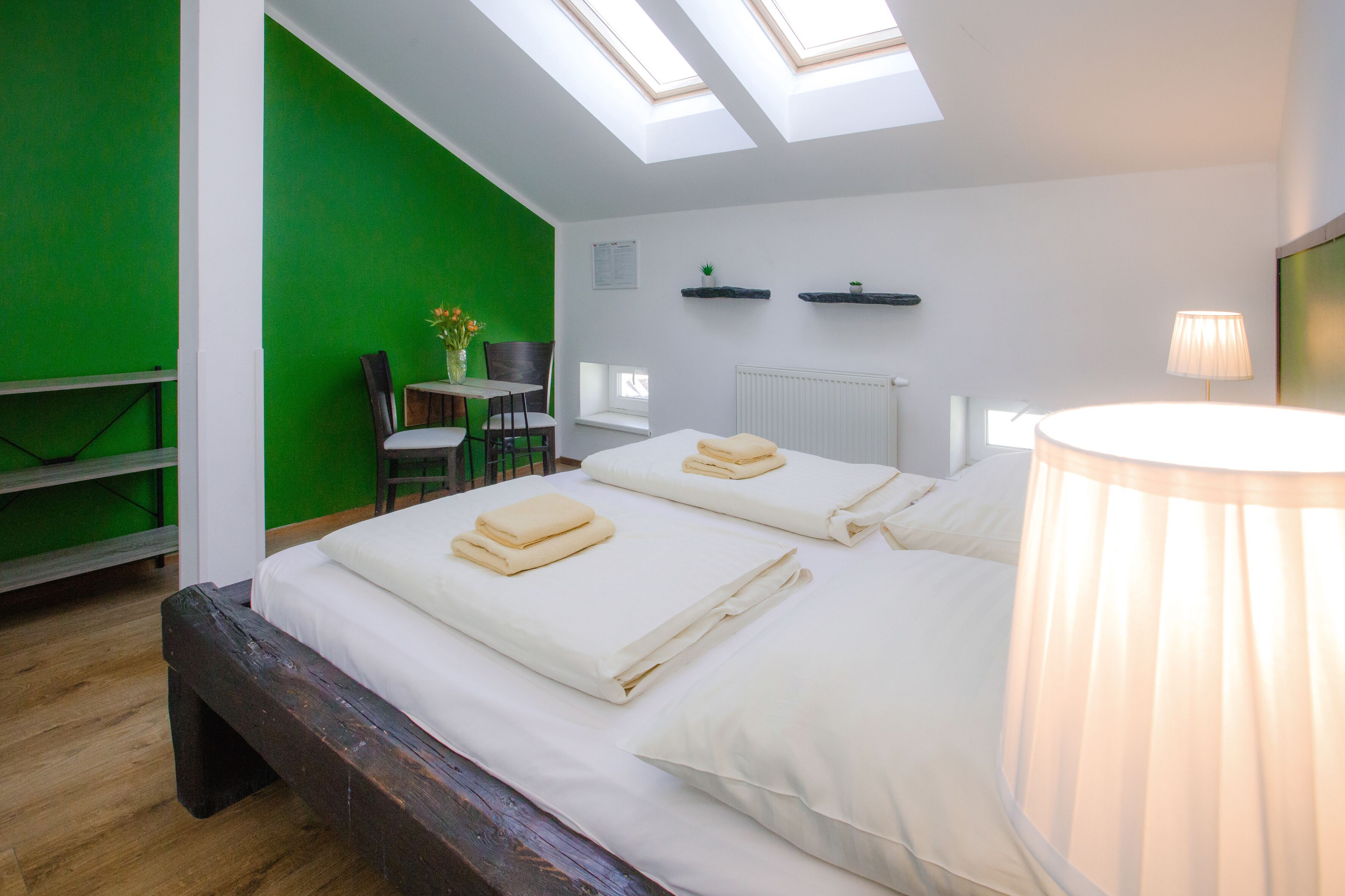 A room with a bed, skylights, a desk, and a chair.