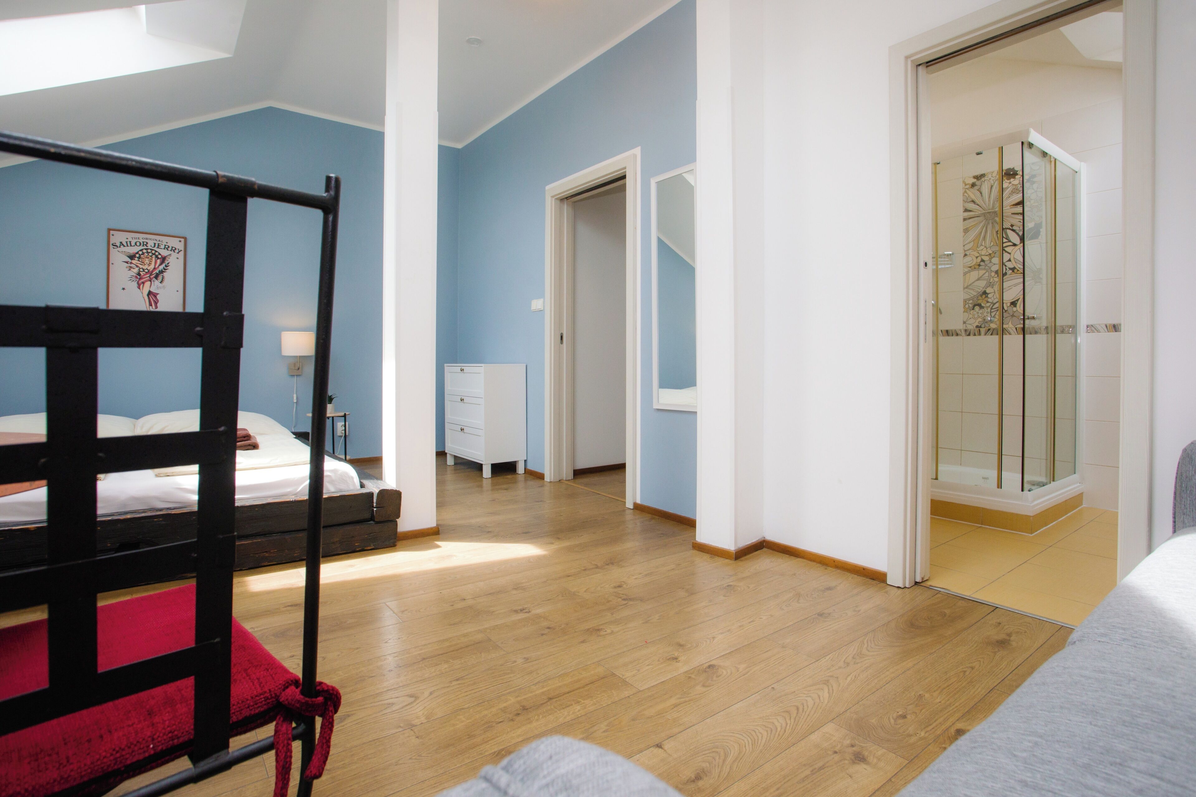Un dormitorio con una cama nido, un escritorio, una silla, un armario y una cabina de ducha de vidrio.