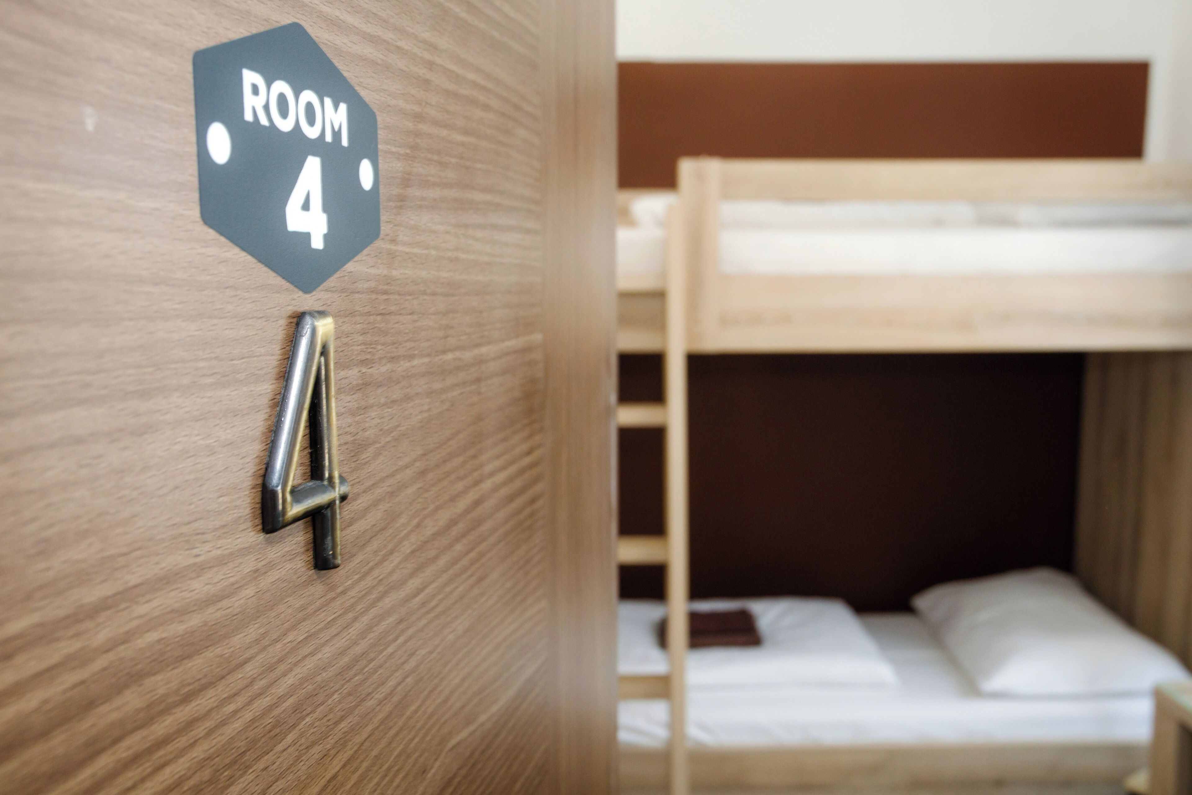 A bunk bed in a room with a wooden door and a sign indicating 'ROOM 4'.