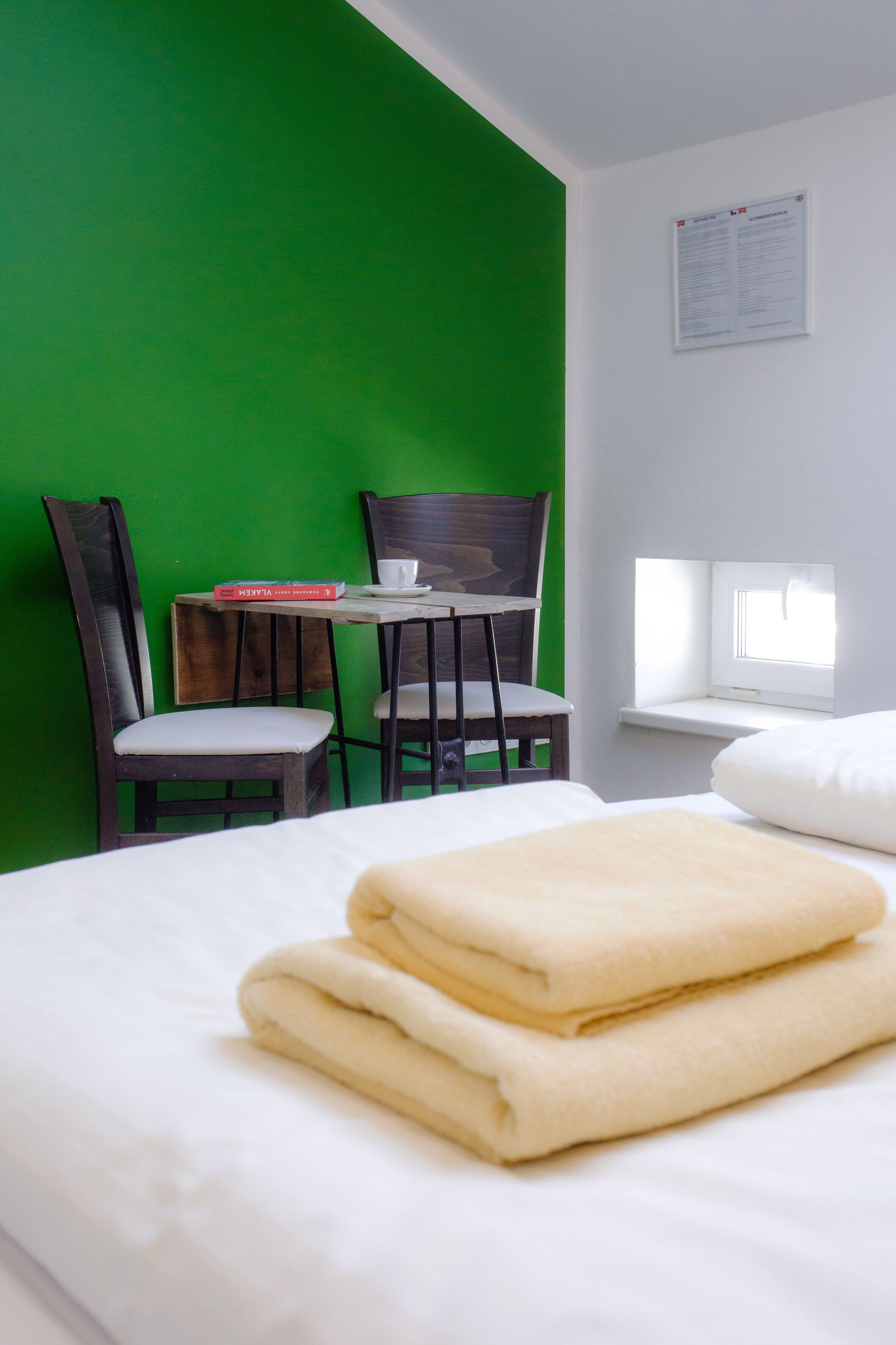 Une pièce avec un lit, une table et des chaises, une fenêtre et un mur vert.