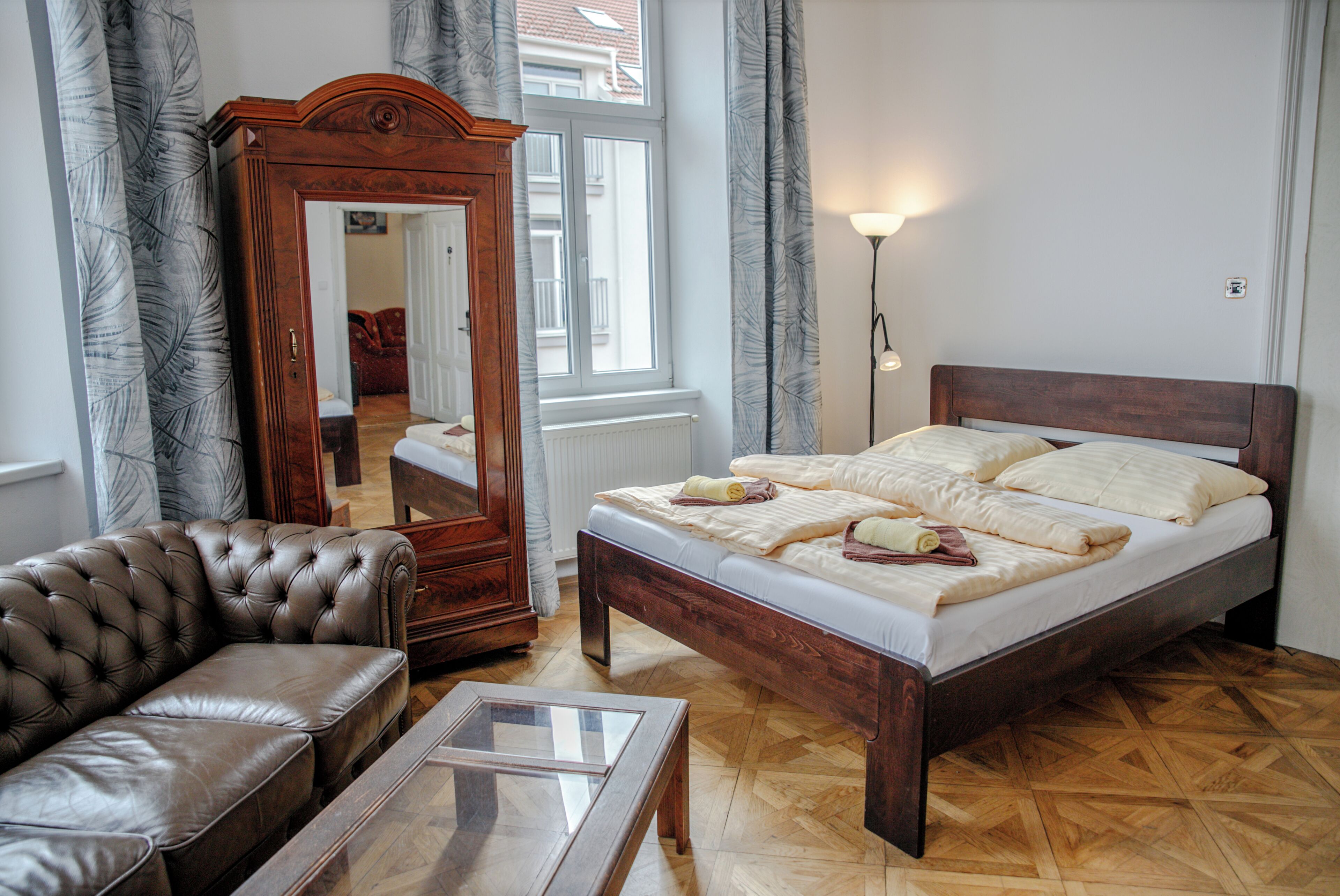 Une chambre à coucher avec un grand lit, une commode en bois, un canapé en cuir et une table basse en verre.