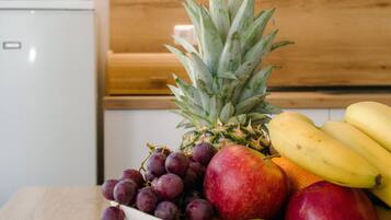 A white bowl with fruits on a wooden table in a kitchen.