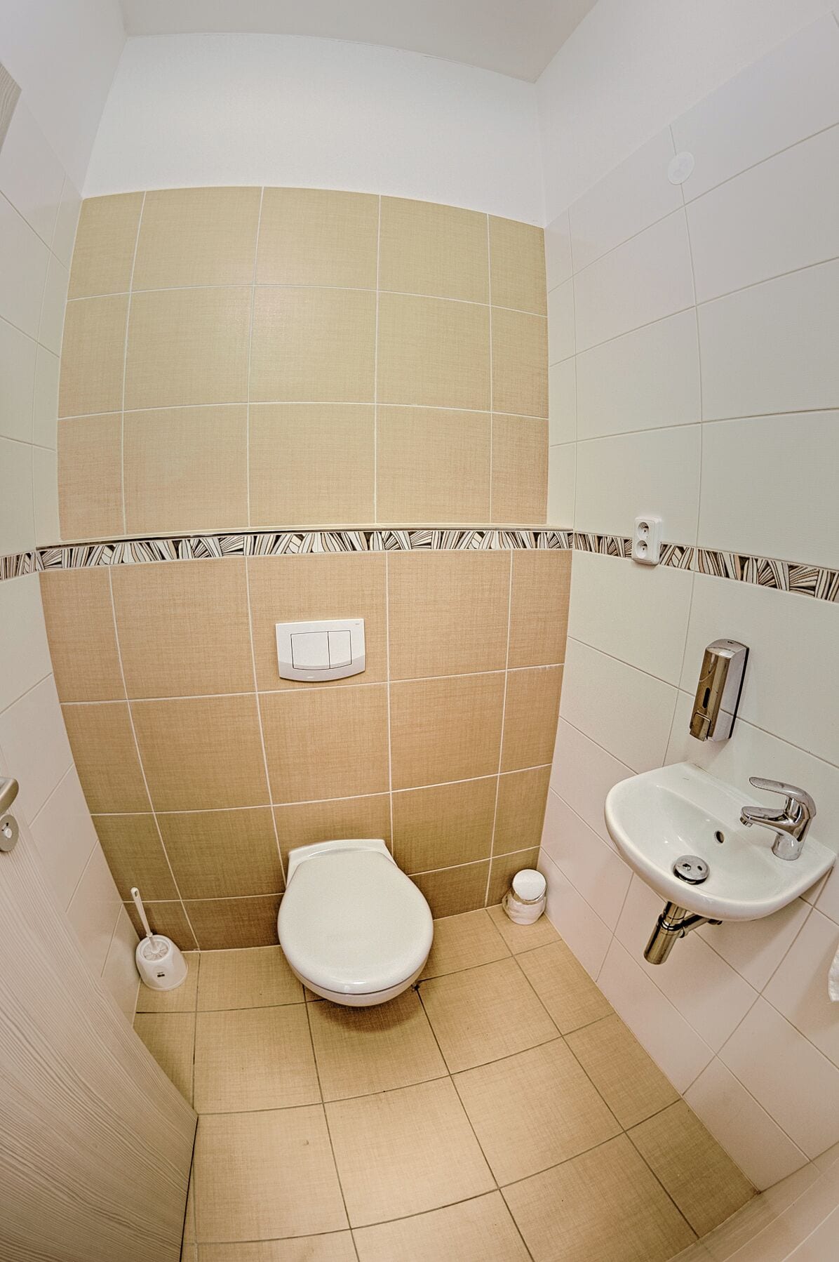 A bathroom with a toilet, sink, and hand dryer.