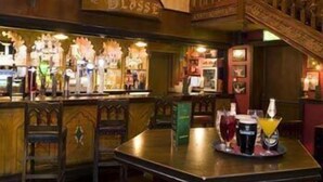 Zona de bar con decoración de madera, una escalera y una barra con bebidas.