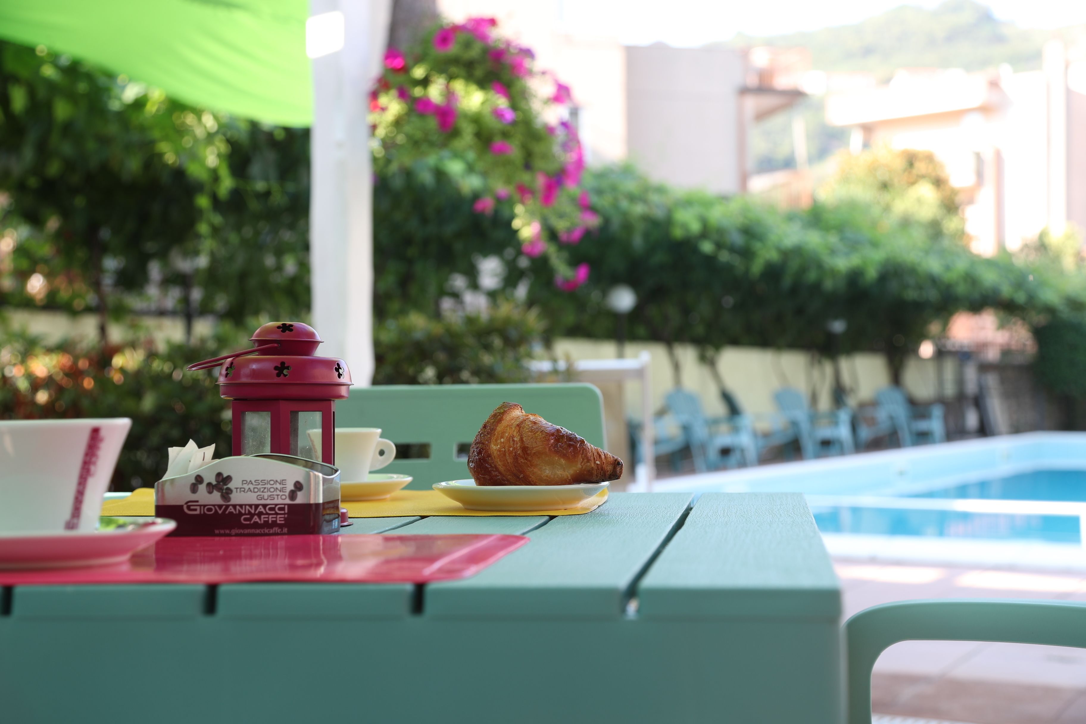 A table with a croissant, a coffee cup, and a menu from Giovannacci Caffè.