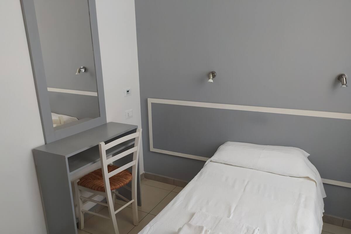 Um quarto com cama, escrivaninha e cadeira.