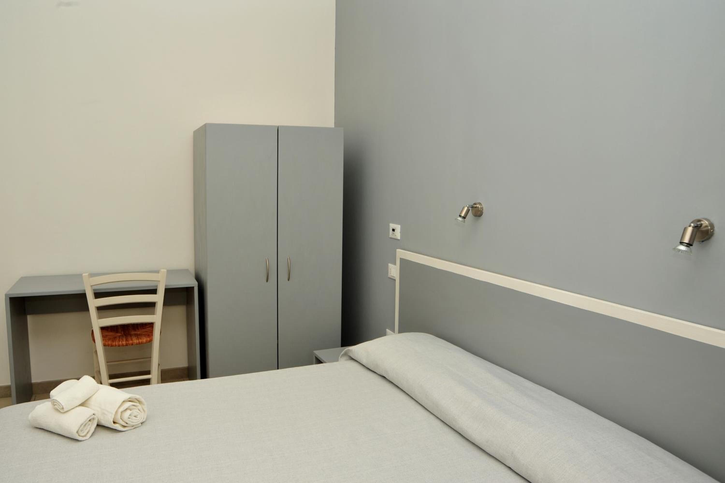 A bedroom with a bed, a desk, and a wardrobe.