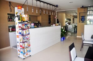 A hotel reception area with a snack bar, a counter, and a seating area with a table and chairs.
