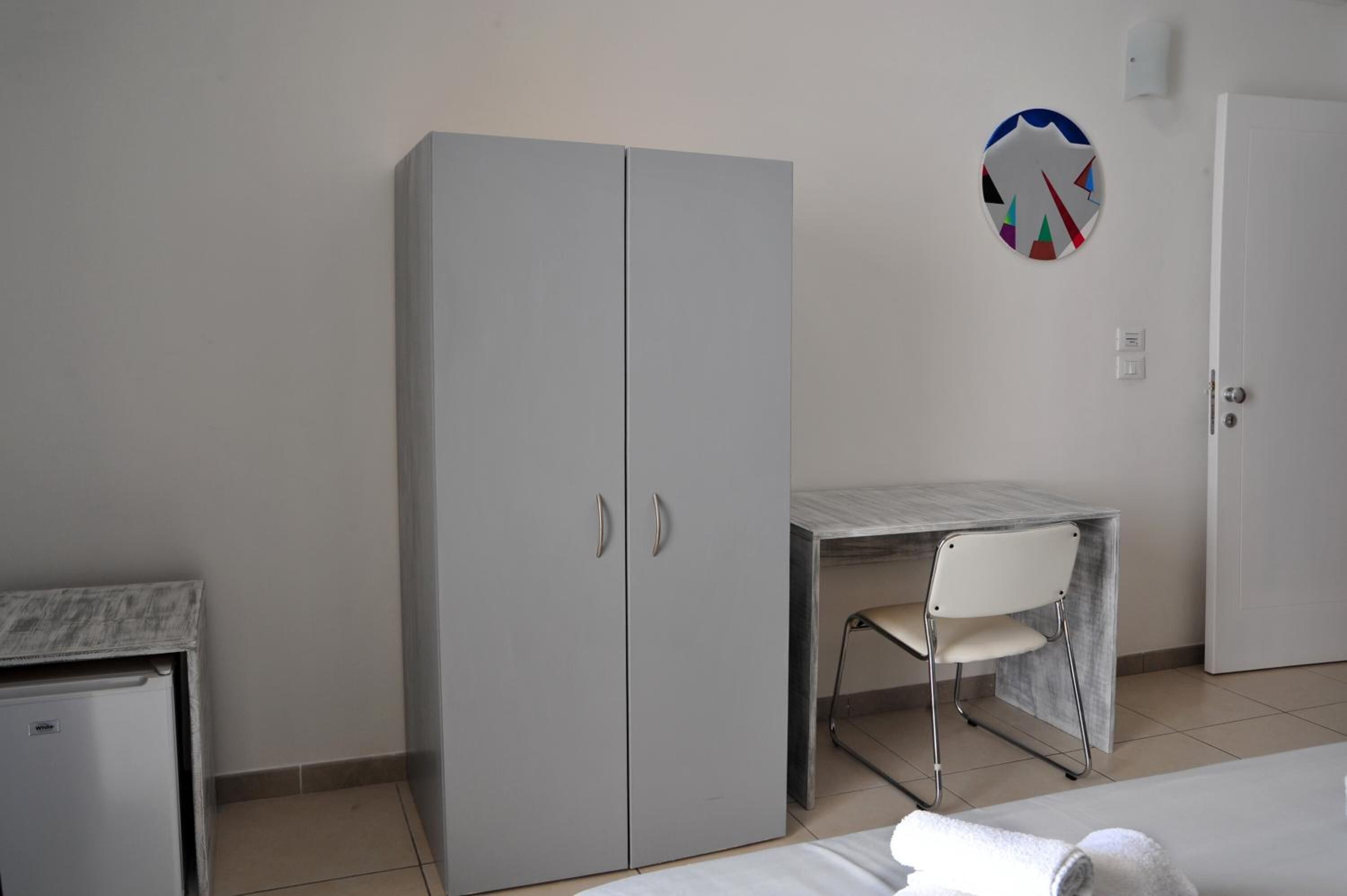 Une chambre à coucher comprenant un lit, une armoire, un bureau avec une chaise et une porte.