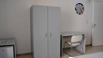 Una camera da letto con un letto, un armadio, una scrivania con una sedia e una porta.