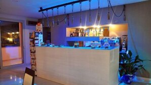 A bar area with a counter, shelves with bottles, and a chair. - La Punta (Otranto)