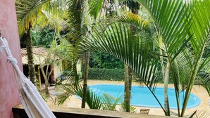 A pool surrounded by lush greenery and a hammock. - Rumo dos Ventos (Paraty)