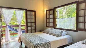 A room with three beds, a hammock, and a view of greenery outside. - Rumo dos Ventos (Paraty)