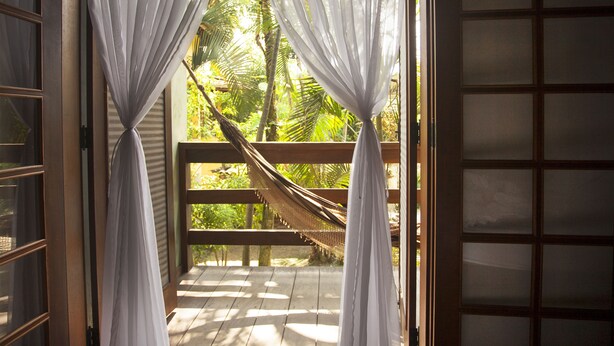 A wooden deck with a hammock and white curtains. - Rumo dos Ventos (Paraty)