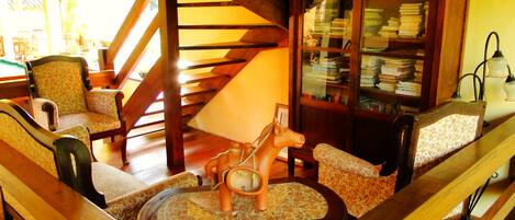 A cozy living room with a wooden staircase, a bookshelf, and a decorative horse statue.