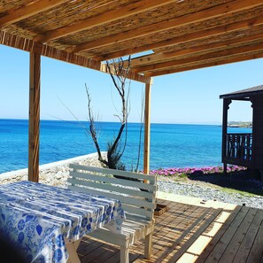 A wooden pergola with a view of the sea, a white bench, and a table with a blue and white tablecloth. - Lipsos Hotel Ata's Place (Karaburun)