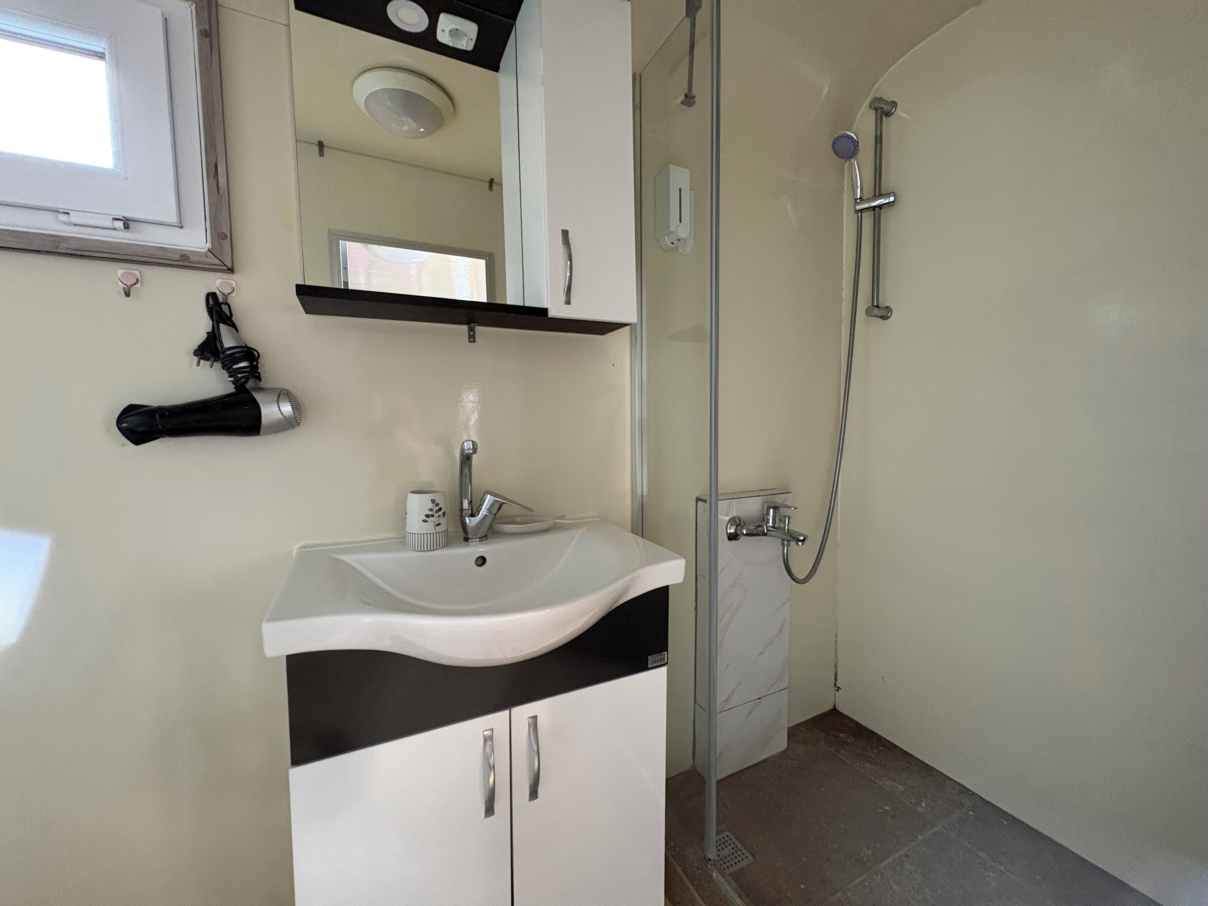 A bathroom with a white sink, a mirror, a shower, and a towel rack.