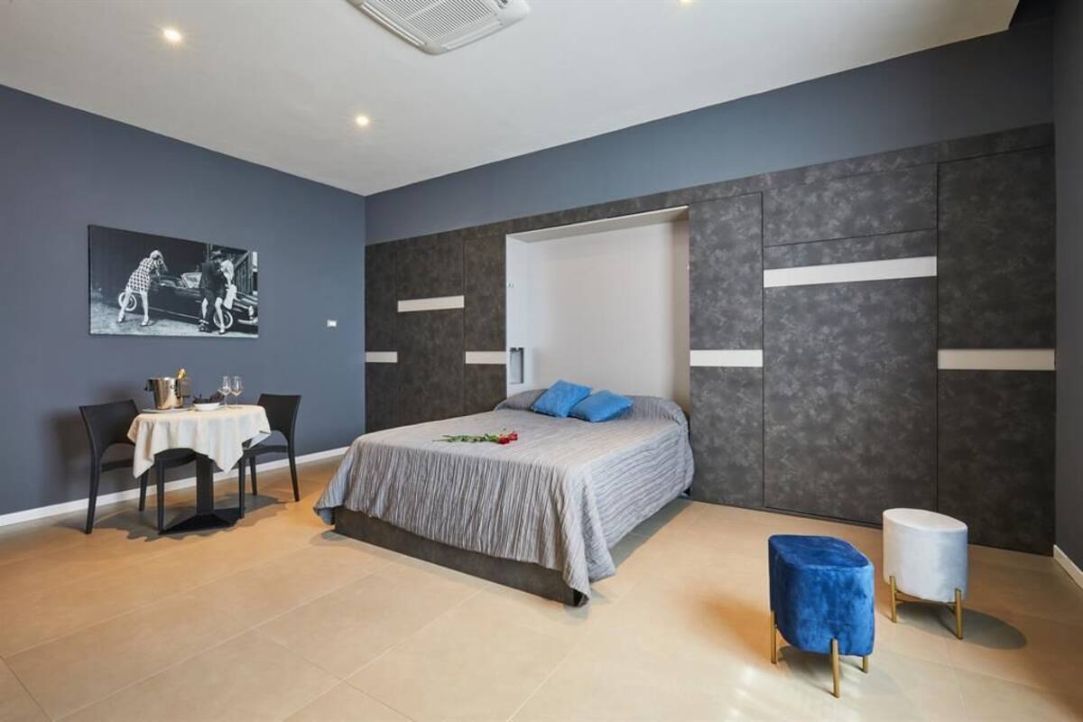 A modern bedroom with a bed, bedside tables, a desk, and a chair.