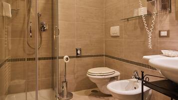 Une salle de bain avec une douche à parois de verre, deux toilettes, un bidet et un lavabo.