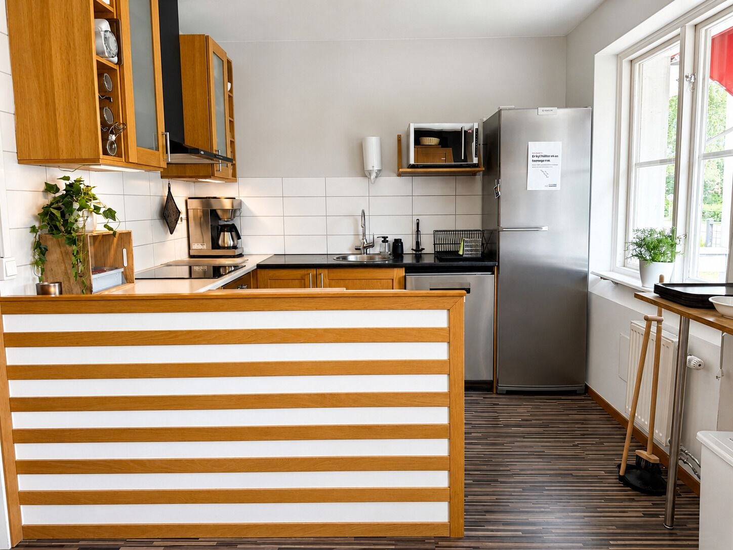 A modern kitchen with wooden cabinets, a stainless steel refrigerator, a microwave, and a coffee maker.