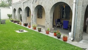 Une cour intérieure agrémentée d’une arche en pierre, de plantes en pot et d’un espace aménagé pour s’asseoir.