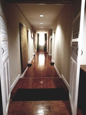 A hallway with wooden flooring, white walls, and a black doormat at the entrance. - Travellers Inn (Quito)