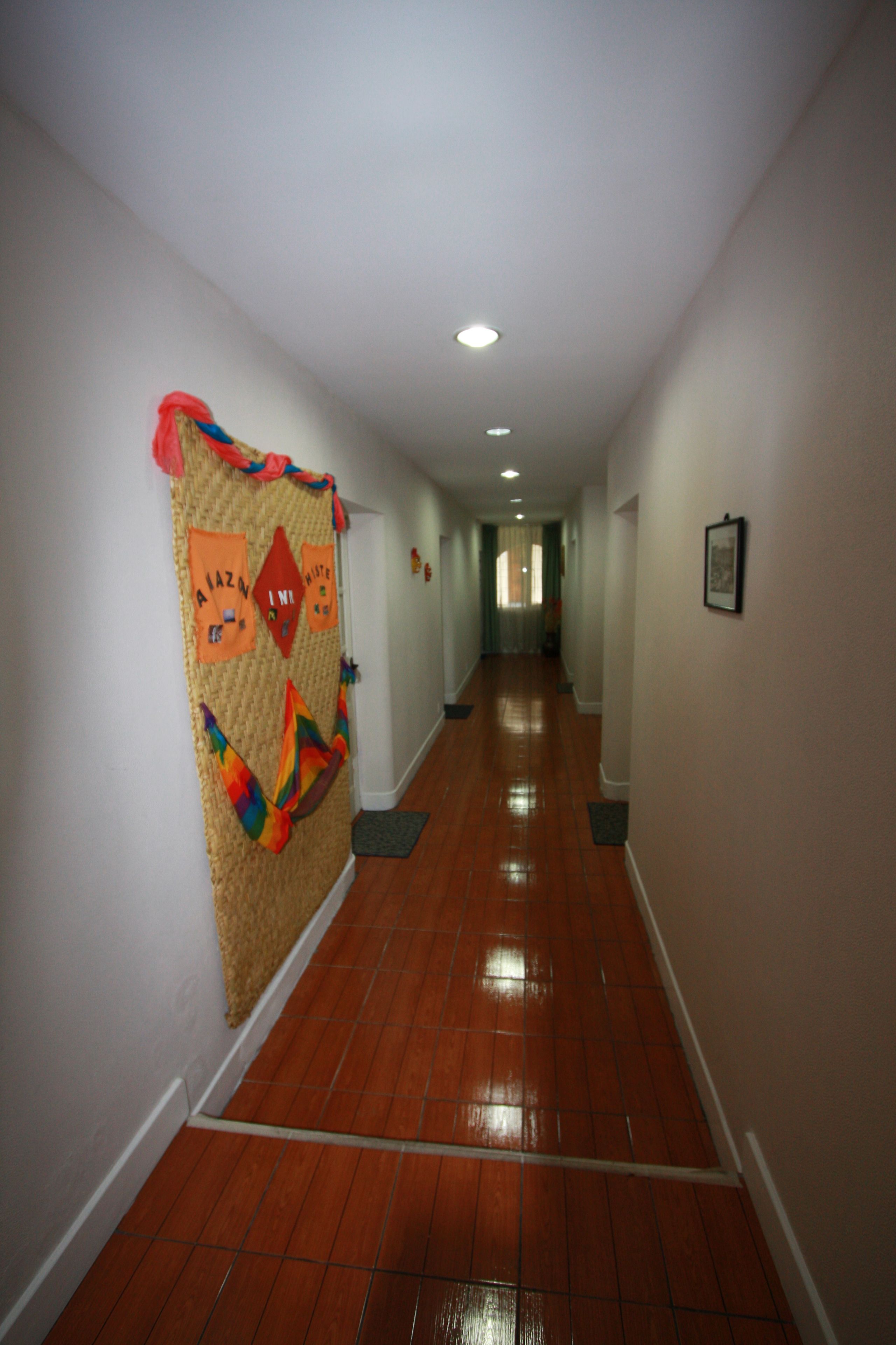 Un couloir avec un sol carrelé, une décoration murale et une porte au fond.
