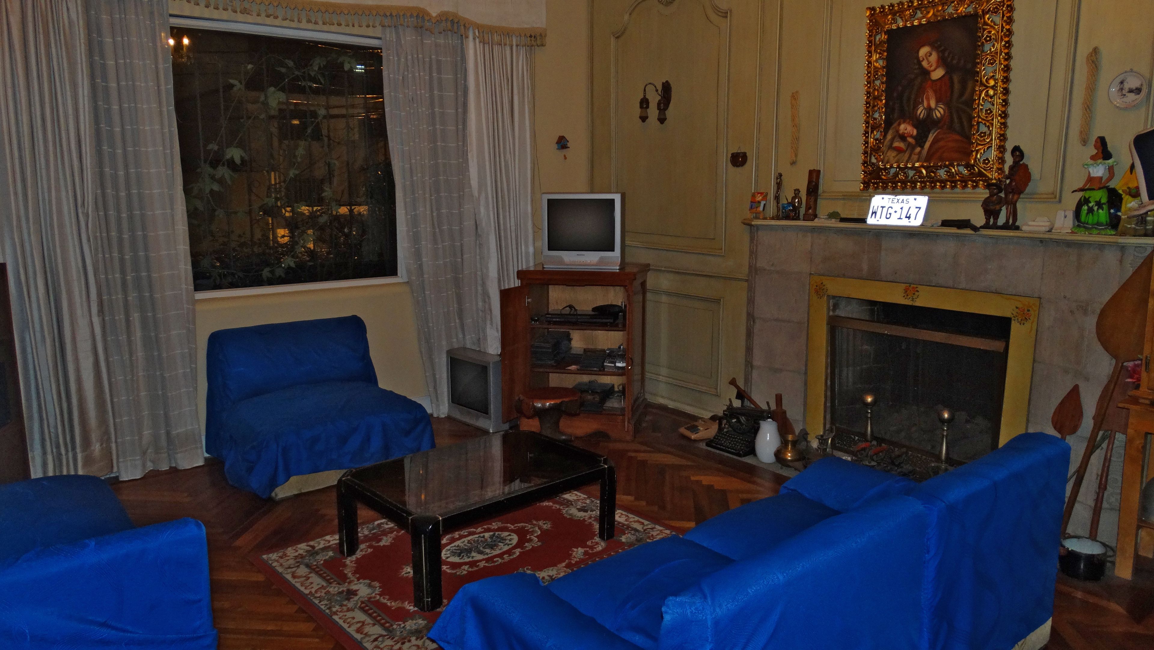 A living room with blue sofas, a television, a fireplace, and a large window with curtains.